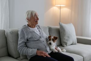 An older woman sitting on a sofa with a small dog