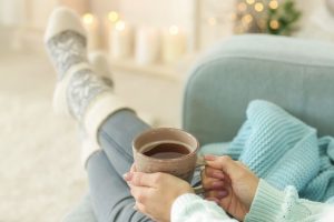 A woman on a sofa, with her feet up and holding a cup of coffee